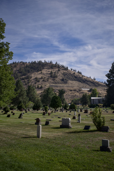 Rows of headstones fill Pilot Butte Cemetery, with Pilot Butte rising behind them.